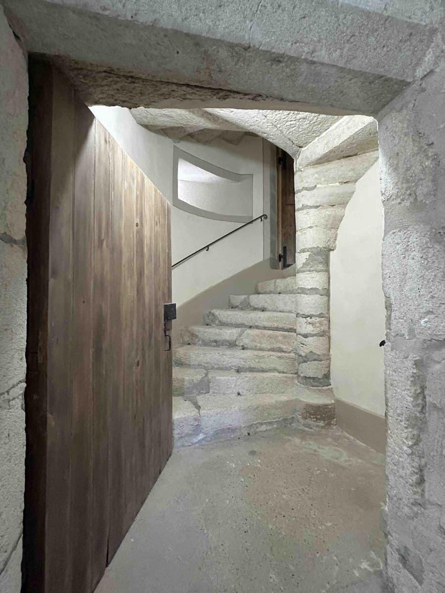 Porte en bois ouverte sur un escalier de pierre ancien